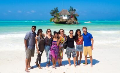 Visitors posing on the beach near The Rock Restaurant in Zanzibar